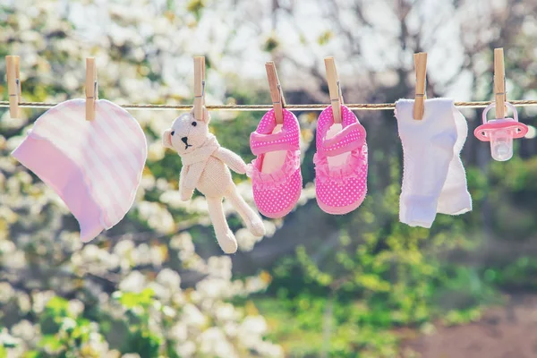 Baby kleding en accessoires wegen op het touw na het wassen in de open lucht. Selectieve focus. — Stockfoto