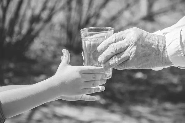 Mormor ger ett glas rent vatten till ett barn. Selektiv inriktning. — Stockfoto