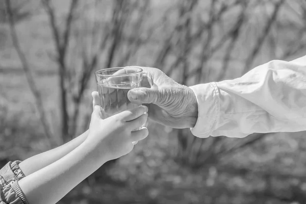 Mormor ger ett glas rent vatten till ett barn. Selektiv inriktning. — Stockfoto