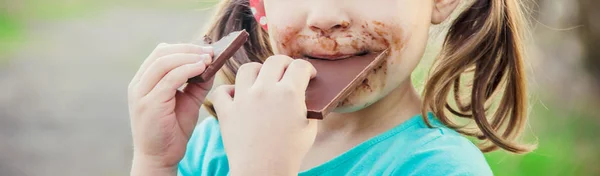 Ένα γλυκό-οδοντωτό παιδί τρώει σοκολάτα. Επιλεκτική εστίαση. — Φωτογραφία Αρχείου