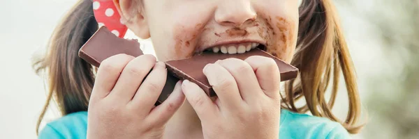 Uma criança de dentes doces come chocolate. Foco seletivo . — Fotografia de Stock