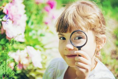 Çocuk bir büyüteç içine bakıyor. Arttır. seçici odak.