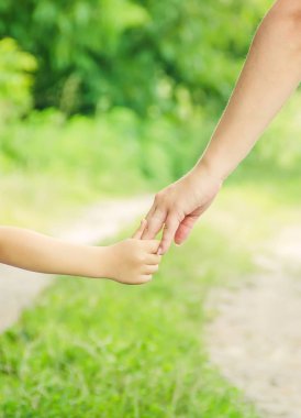 Anne ve kızı el ele tutuşarak yolda yürüyor.