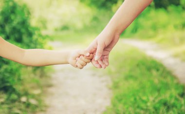 Anne ve kızı el ele tutuşarak yolda yürüyor.