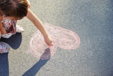 çocuk asfalt kalp tebeşir boyar. Seçici odak.