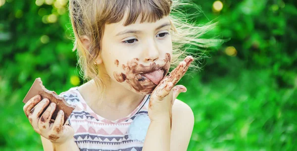 Un enfant à dents sucrées mange du chocolat. Concentration sélective . — Photo