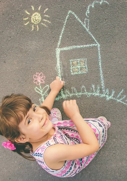 El niño dibuja la casa con tiza sobre el asfalto. Enfoque selectivo . —  Fotos de Stock