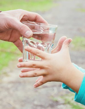 Baba çocuk bir bardak su verir. Seçici odak.