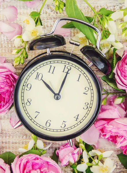 Lente bloemen en wekker. De tijd wijzigen. — Stockfoto