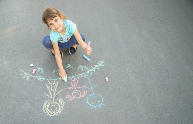 Çocuk tebeşirle kaldırımda bir aile çizer. Seçici odaklama.