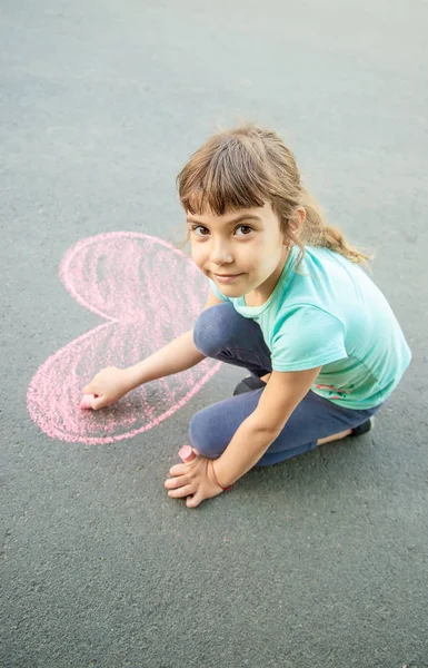El niño pinta la tiza en el corazón de asfalto. Enfoque selectivo . —  Fotos de Stock