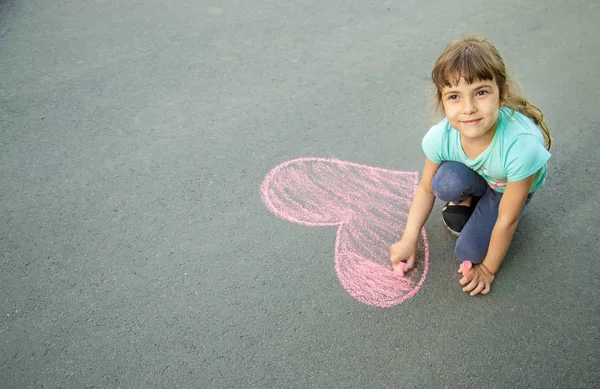 子供は、アスファルトの心にチョークを描画します。選択と集中. — ストック写真