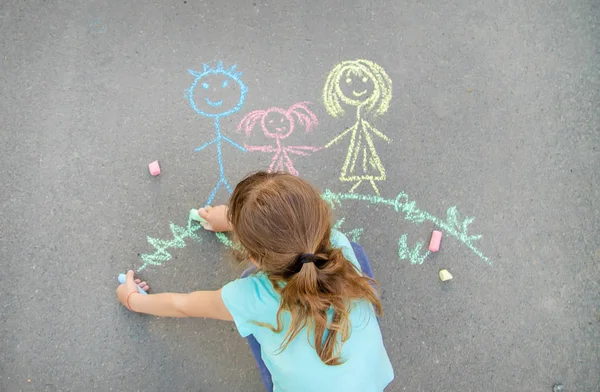 Das Kind zeichnet eine Familie mit Kreide auf den Bürgersteig. Selektiver Fokus. — Stockfoto
