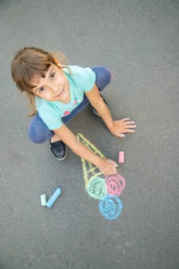 Çocuk tebeşirle asfalta dondurma çizer. Seçici odaklama.