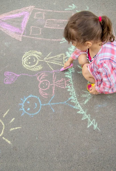 L'enfant dessine une famille sur le trottoir avec de la craie. Concentration sélective . — Photo