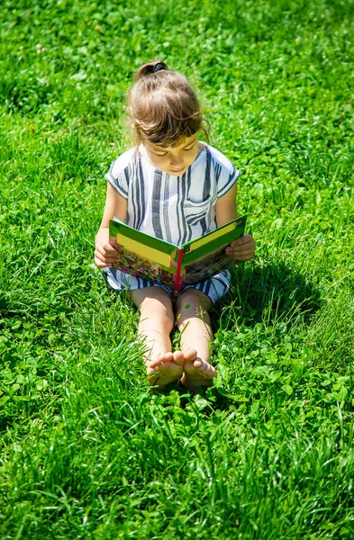 Criança lendo um livro na natureza. Foco seletivo . — Fotografia de Stock