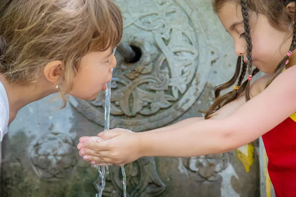 Kinder trinken Wasser aus einer Quelle in Borjomi, Georgien. Selektiver Fokus. — Stockfoto