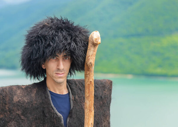 Georgian man in a beech costume on a background of mountains. Selective focus.