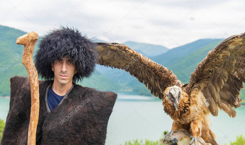 Georgian man in a beech costume on a background of mountains. Selective focus.