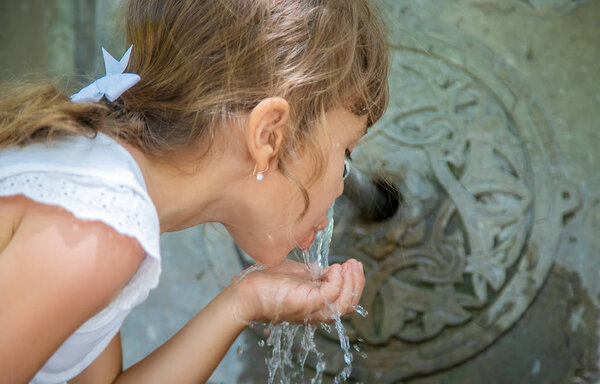 children drink water from a spring in Borjomi, Georgia. Selective focus.