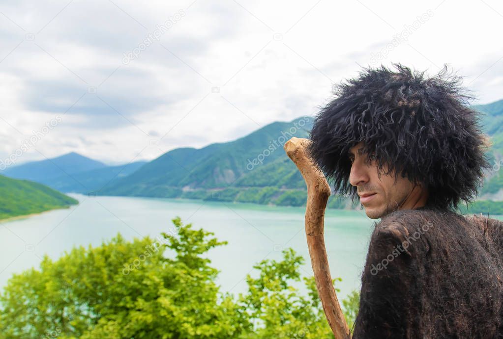 Georgian man in a beech costume on a background of mountains. Selective focus.