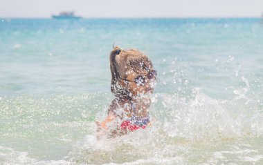 çocuk denize sprey yapar. Seçici odaklama.