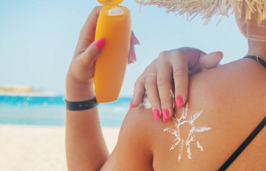 Sahildeki kızlar derilerine güneş kremi takarlar. Seçici odaklama.