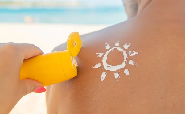 浜辺の女の子は、男性の皮膚に日焼け止めを塗ります。選択フォーカス. — ストック写真