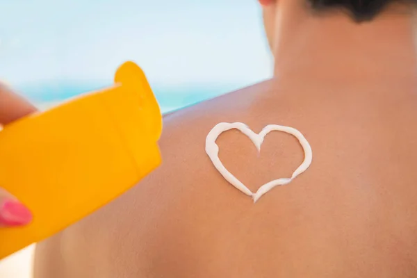 La fille sur la plage applique de la crème solaire sur la peau d'un homme. Concentration sélective . — Photo