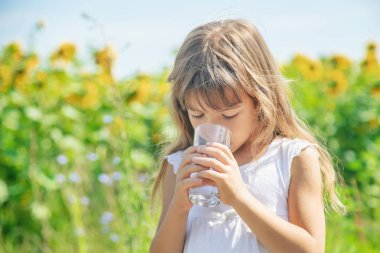 Bir çocuk tarlanın arka planında su içer. Seçici odaklama.