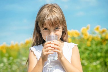 Bir çocuk tarlanın arka planında su içer. Seçici odaklama.