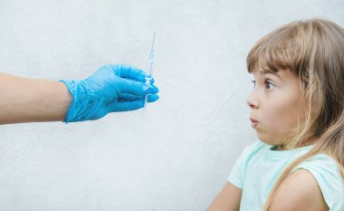 Doktor çocuğa koluna bir iğne yapıyor. Seçici odaklama.