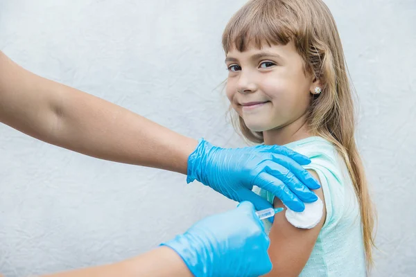 Il medico somministra al bambino un'iniezione nel braccio. Focus selettivo . — Foto Stock