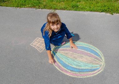 Çocuk kaldırıma tebeşirle çiziyor. Seçici odak.