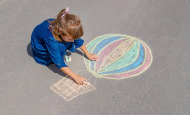 Çocuk kaldırıma tebeşirle çiziyor. Seçici odak.