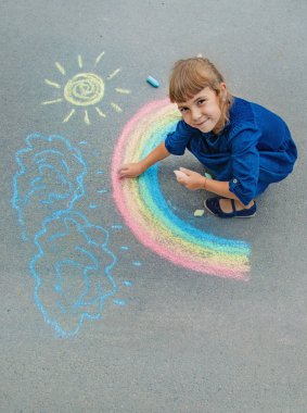 Çocuk kaldırıma tebeşirle çiziyor. Seçici odak.