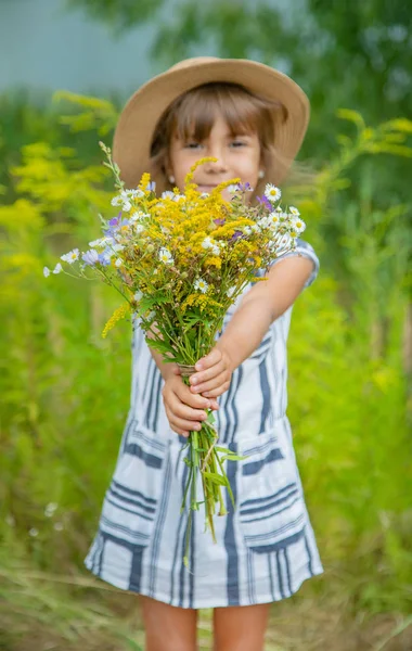 Fille tenant des fleurs sauvages dans les mains d'un enfant. Concentration sélective . — Photo