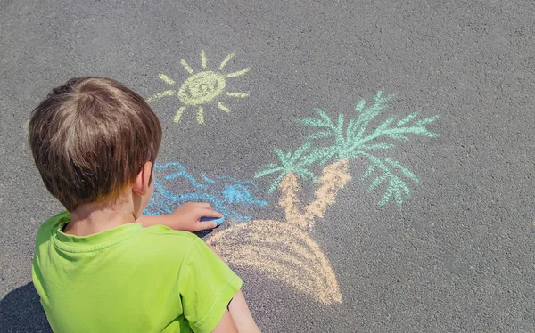 Kind zeichnet mit Kreide auf den Bürgersteig. Selektiver Fokus. — Stockfoto