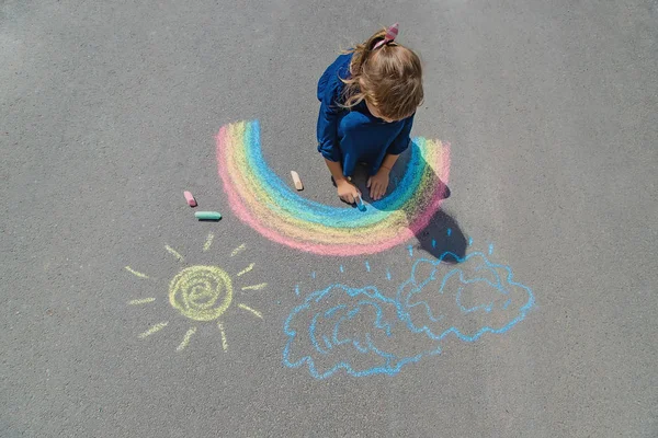 Kind zeichnet mit Kreide auf den Bürgersteig. Selektiver Fokus. — Stockfoto