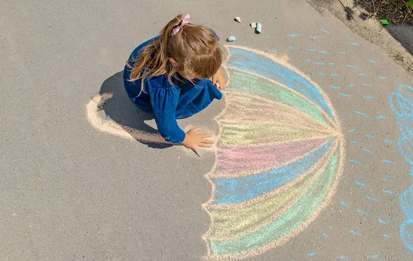 Enfant dessine à la craie sur le trottoir. Concentration sélective. — Photo