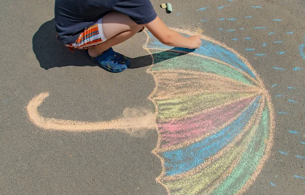 A gyerek krétával rajzol a járdán. Szelektív fókusz. — Stock Fotó