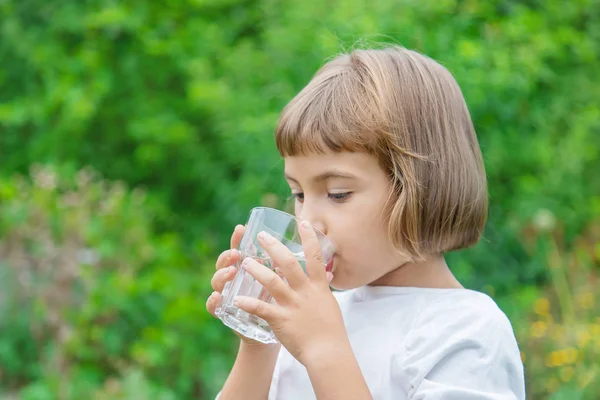 Barn dricker vatten från ett glas. Selektivt fokus. — Stockfoto