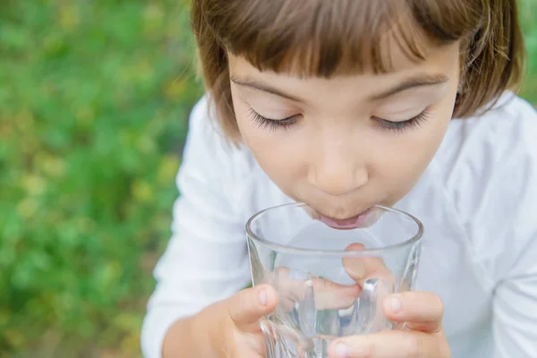 Niño bebe agua de un vaso. Enfoque selectivo . — Foto de Stock