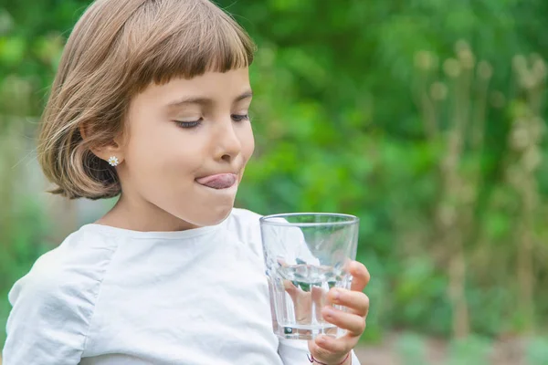 Barn dricker vatten från ett glas. Selektivt fokus. — Stockfoto