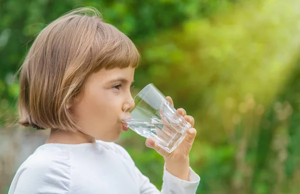 Kind trinkt Wasser aus einem Glas. Selektiver Fokus. — Stockfoto