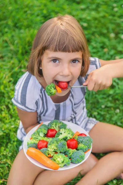 Dziecko zjada warzywa brokuły i marchew. Selektywna koncentracja. — Zdjęcie stockowe