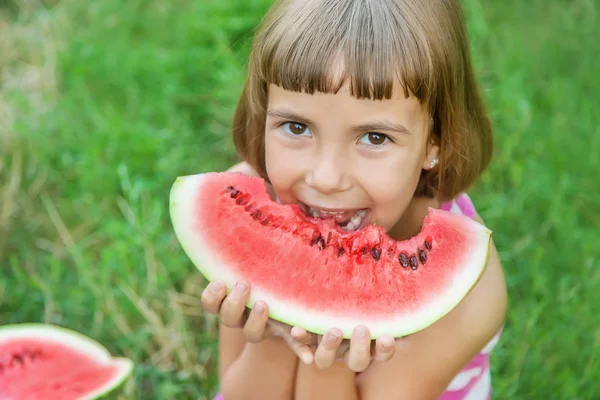 子供は庭でスイカを食べる。選択フォーカス. — ストック写真