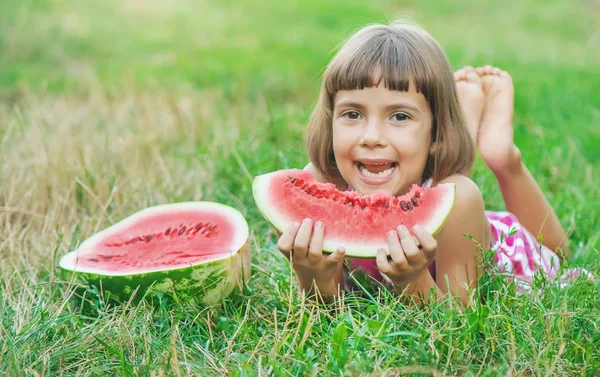 Criança come uma melancia no jardim. Foco seletivo . — Fotografia de Stock