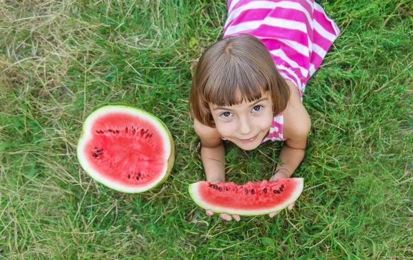 Kind eet een watermeloen in de tuin. Selectieve focus. — Stockfoto