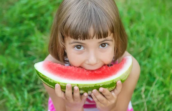 Criança come uma melancia no jardim. Foco seletivo . — Fotografia de Stock